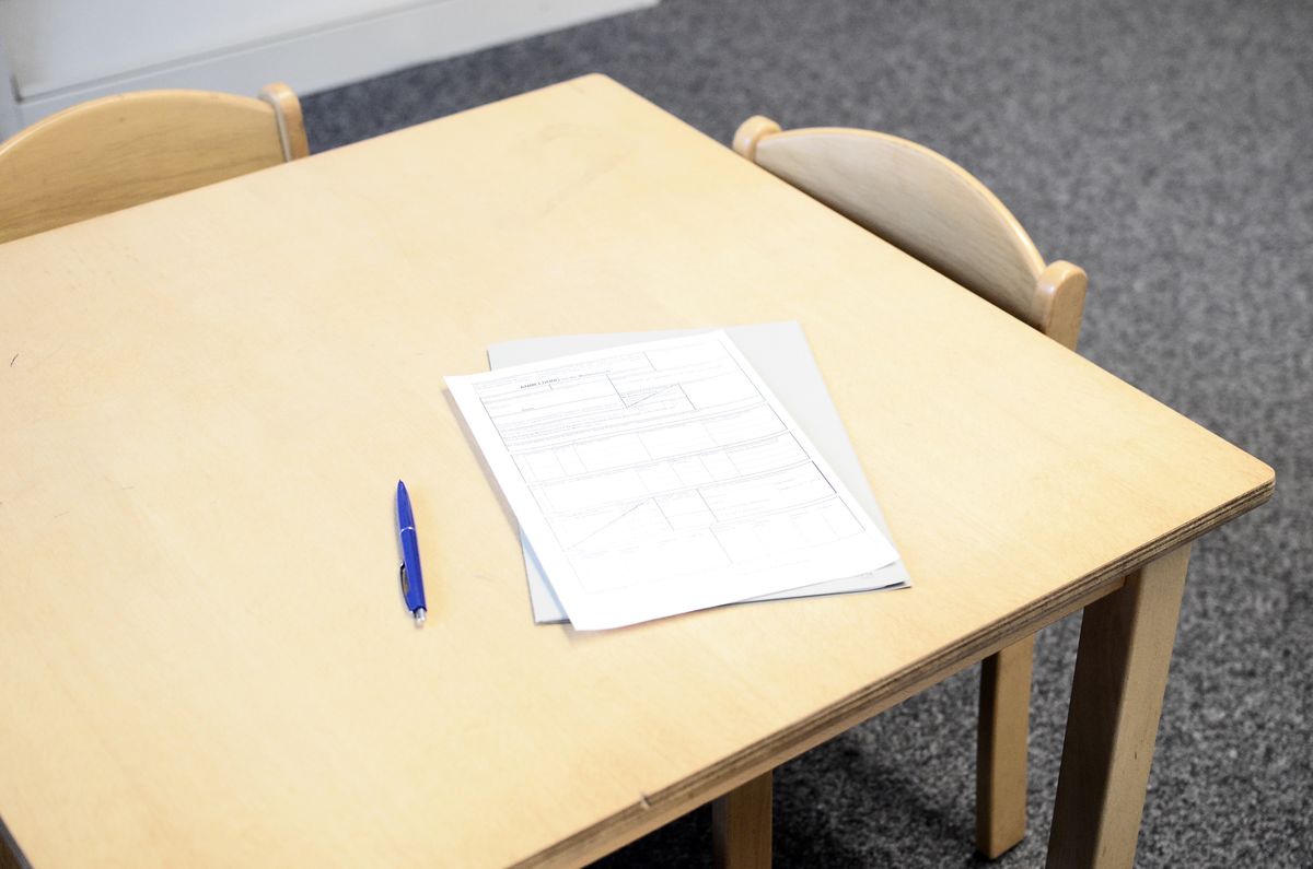 Illustrative stock photograph of papers and a pen on a classroom desk.